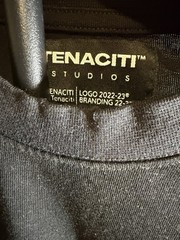 Tenaciti Studios t-shirt features a large fuzzy “T” logo on the right chest SZ S